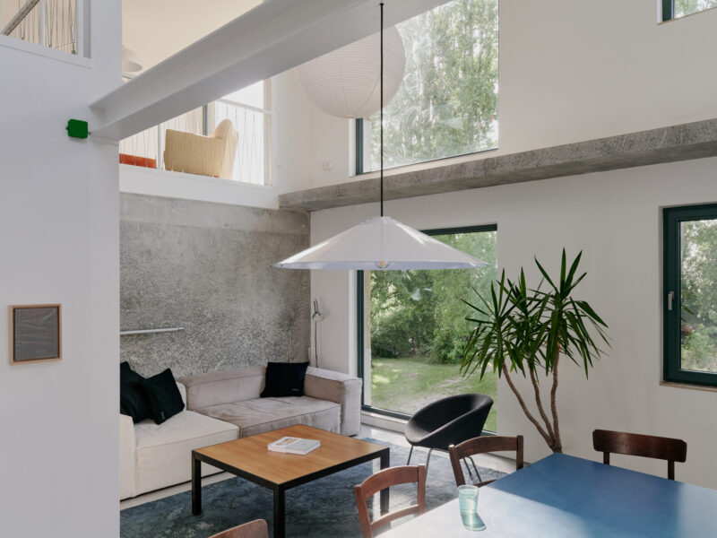Modern interior of Palais Brut featuring a minimalist living area with a sofa, dining table, and large windows.