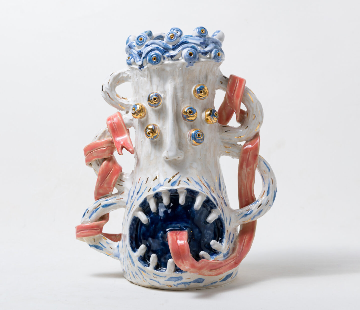 Ceramic vessel with a monster-like face, blue and pink accents, and protruding eyes and tentacle-like features.