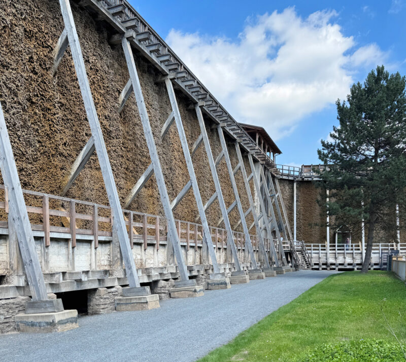 Gradierwerk structure in Bad Dürrenberg Kurpark, featuring wooden supports and a gravel path beside green grass.