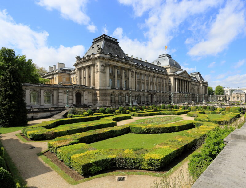 Palace with ornate architecture surrounded by manicured gardens under a blue sky in Brussels, Belgium.