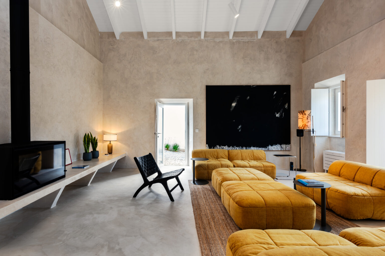 Modern living room featuring yellow sectional sofas, a black accent wall, and minimalist decor, with natural light from wi...