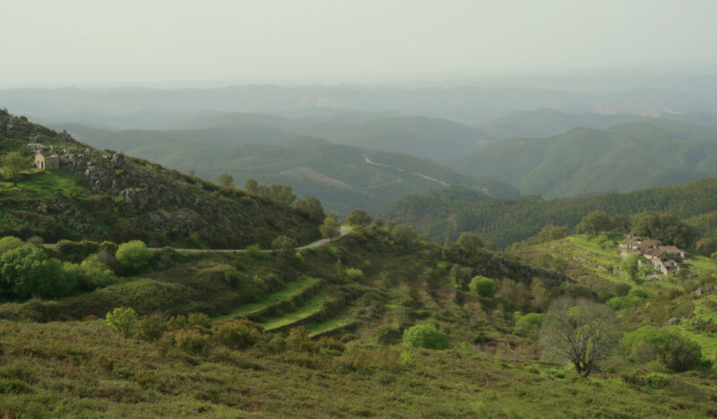 Lush green hills and winding roads in the Serra de Monchique, leading to the Cascata do Barbelote.