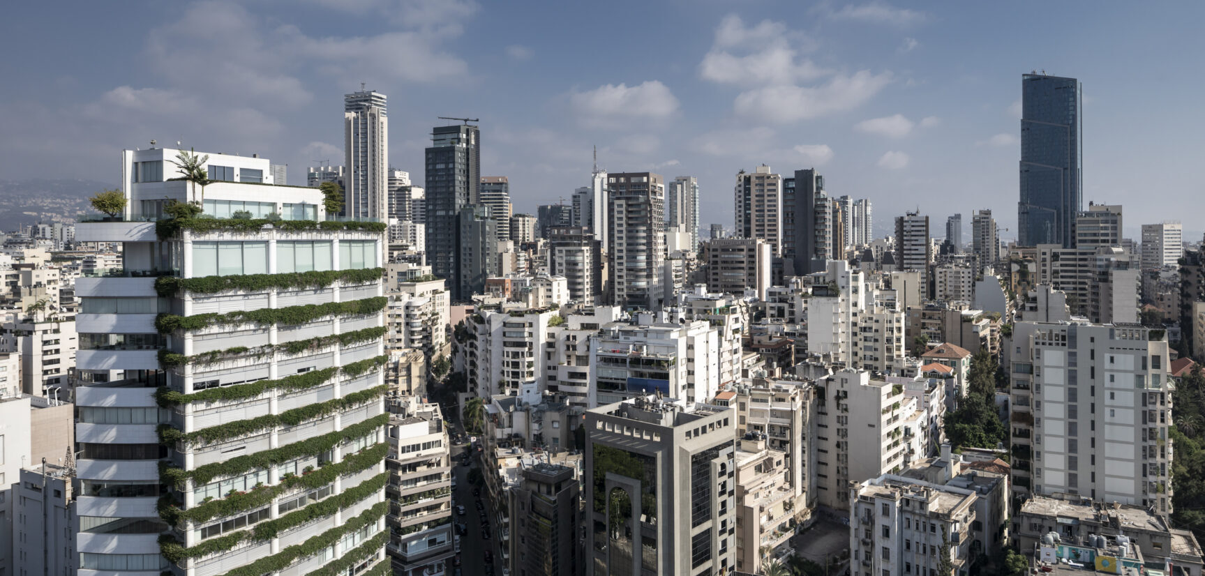 Panoramic view of Beirut's skyline featuring modern buildings and greenery against a blue sky.