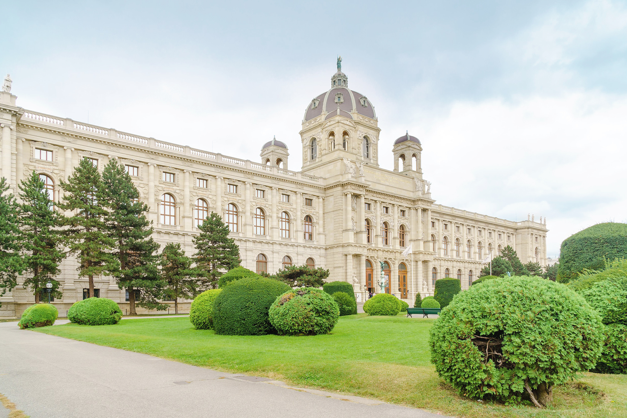 Historic Kunsthistorisches Museum in Vienna, featuring a grand facade and manicured gardens with rounded hedges.