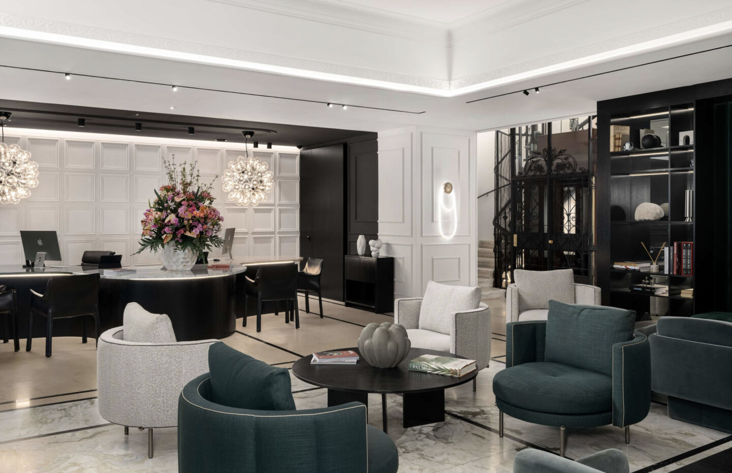 Modern hotel lobby featuring stylish seating, a floral arrangement, and a reception desk. Elegant decor with soft lighting.