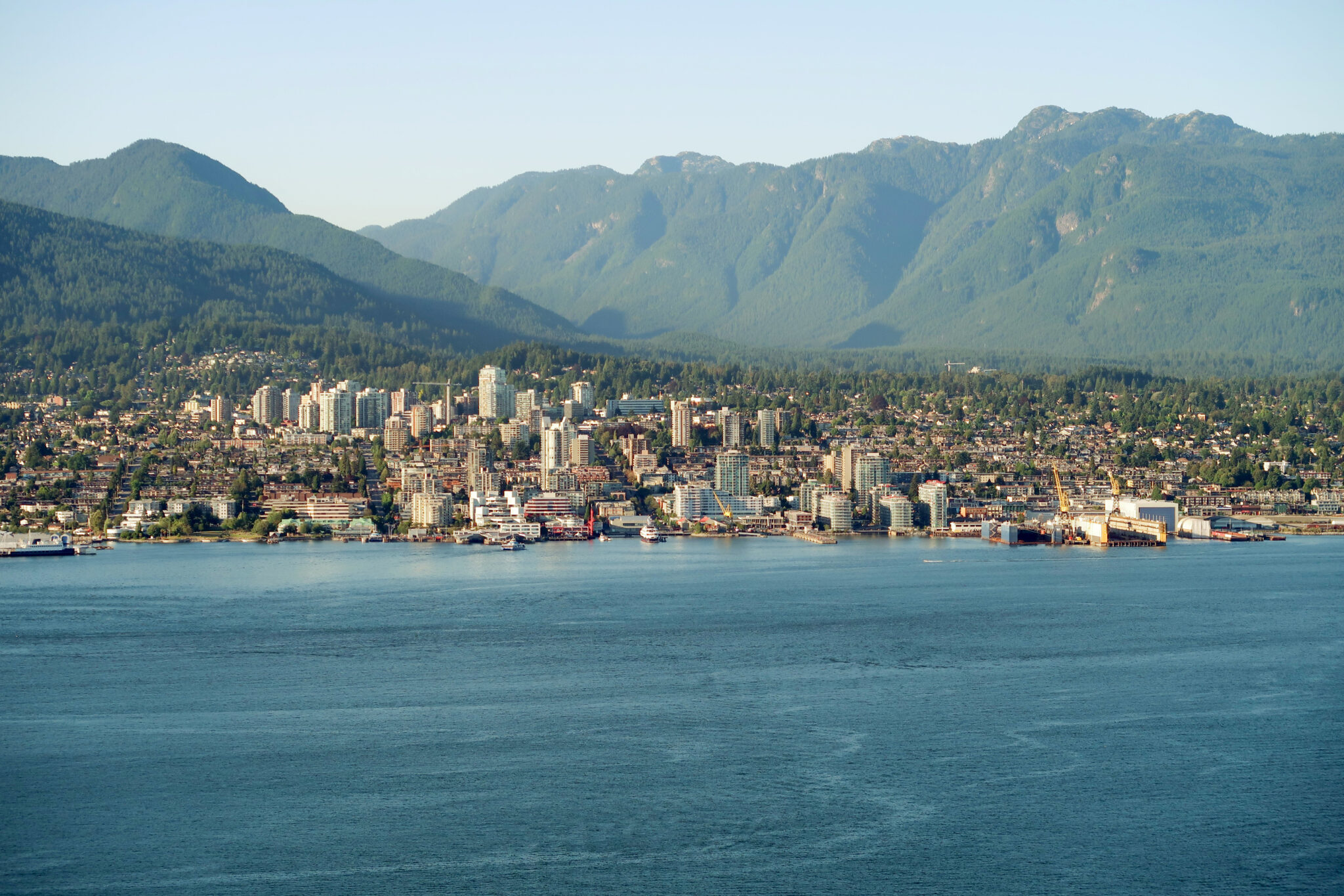 View of North Vancouver with mountains in the background, showcasing the city skyline and waterfront.