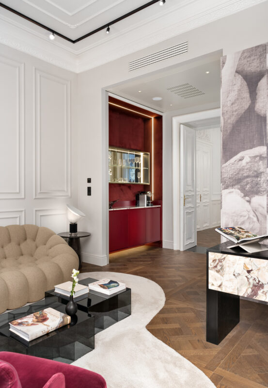 Luxurious hotel suite interior featuring a plush sofa, coffee station, and elegant decor in warm tones.