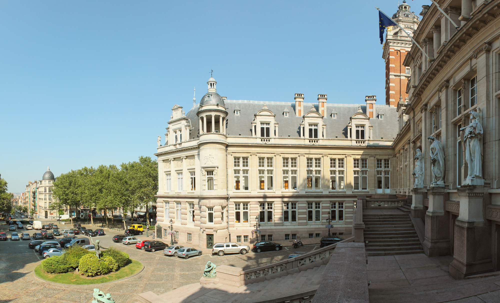 Panoramic view of Hôtel de Ville in Saint-Gilles, showcasing its architecture and surrounding square with parked cars.