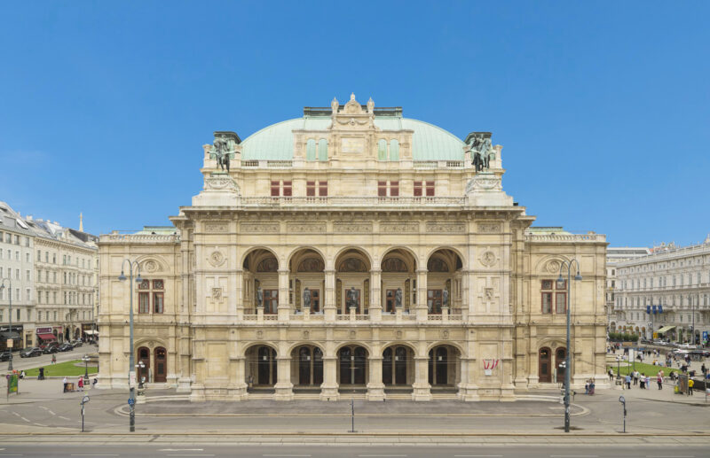 Historic façade of the Vienna State Opera, showcasing its ornate architecture against a clear blue sky.