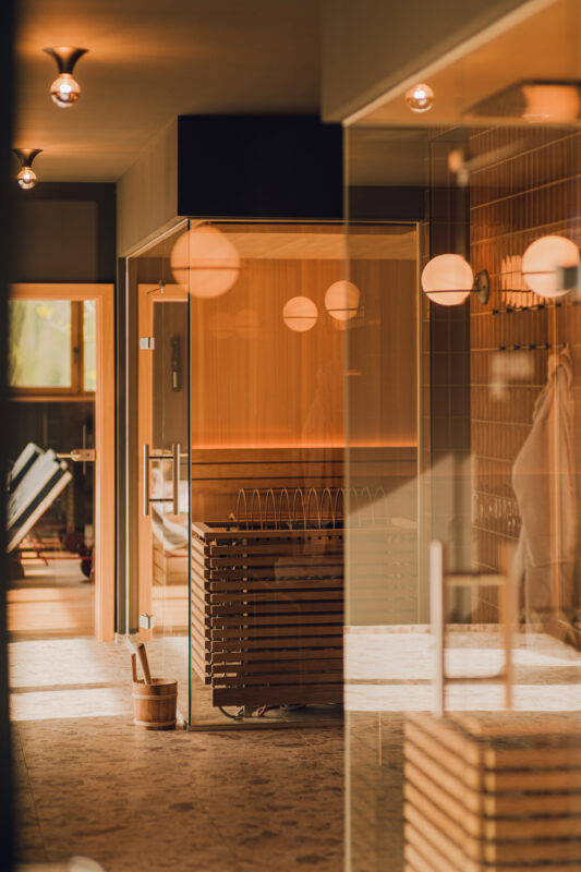 Warm-toned interior of a spa with wooden accents, featuring a sauna and soft lighting.