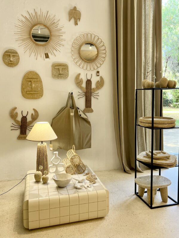 Decorative interior scene featuring a light-colored wall with wall art, a lamp, and a display of natural materials.