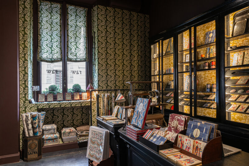 Colorful patterned wallpaper and shelves filled with decorative items in a stylish shop interior.