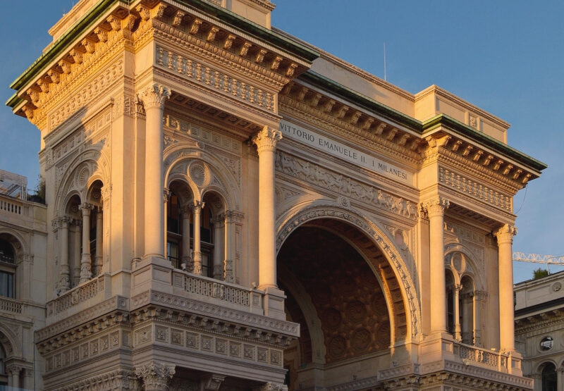Architectural detail of the Galleria Vittorio Emanuele II in Milan, showcasing ornate stonework and arches.