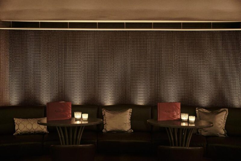 Cozy lounge area at Kurhaus Binz with dim lighting, two tables, and decorative cushions.