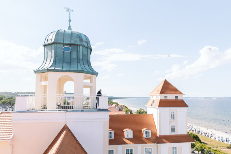 View of the Kurhaus Binz with a distinctive green dome, overlooking the beach and sea under a clear sky.