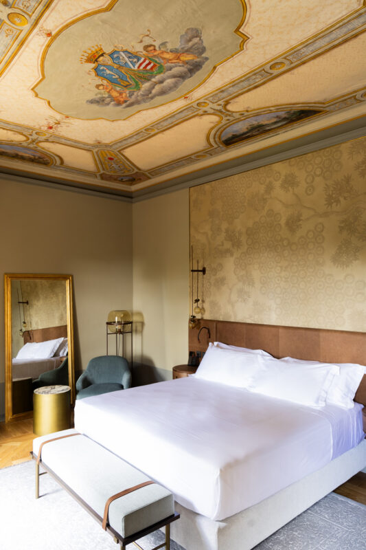 Elegant bedroom in Borgo Dei Conti Resort featuring a large bed, ornate ceiling, and a mirror.