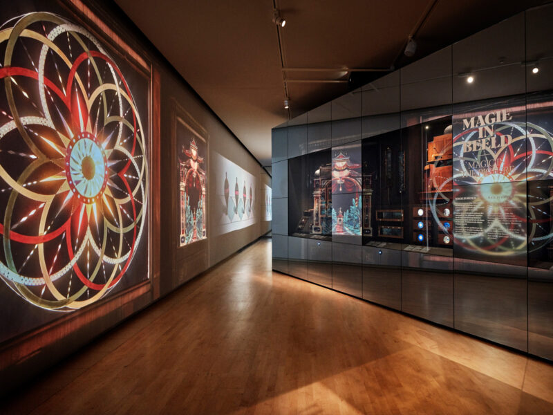 Exhibition space featuring colorful circular patterns and illuminated displays, titled "DeGroteIllusieweb" by Bastiaan Van...
