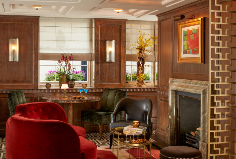 Elegant bar interior at Flemings Mayfair, featuring plush seating, a fireplace, and decorative art.