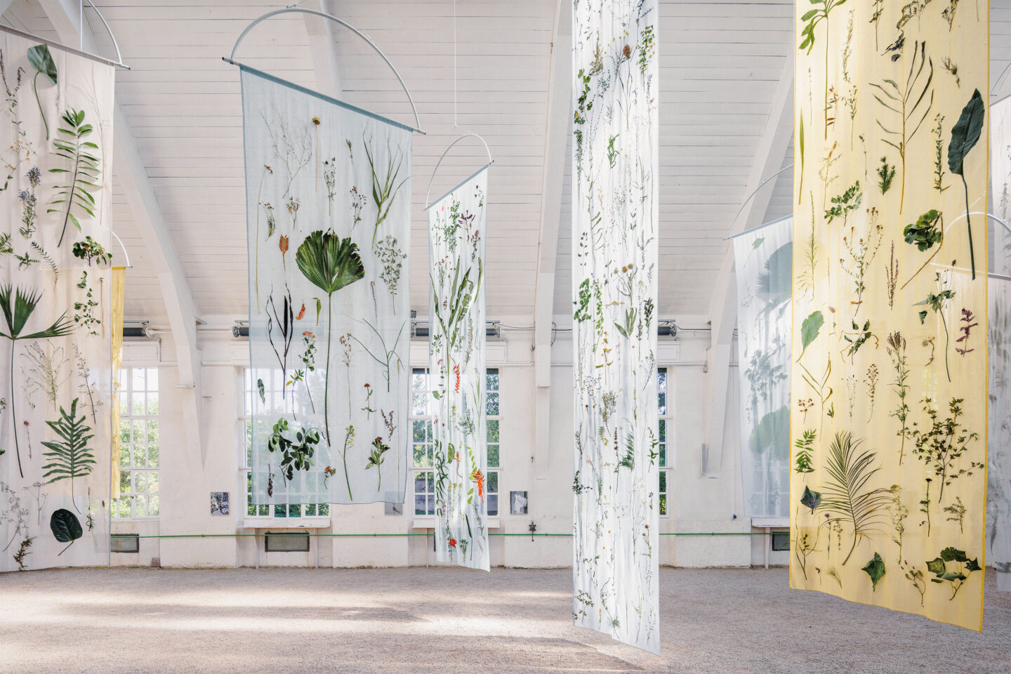 Hanging fabric panels featuring botanical prints in a bright, airy gallery space.