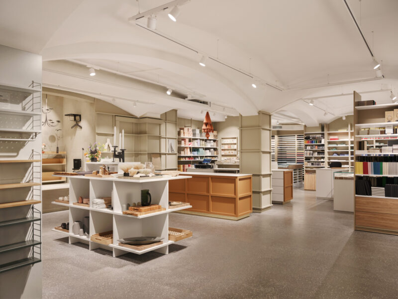 Modern retail space with minimalist design, featuring shelves of products and a central display table.