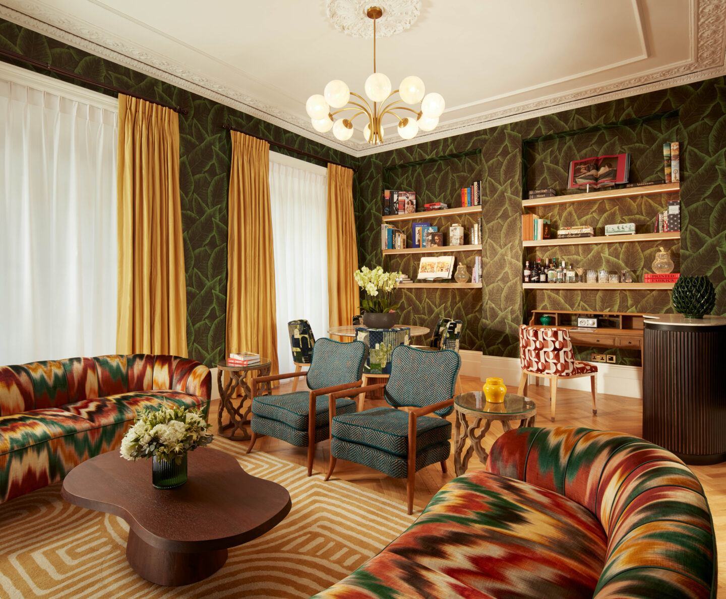 Luxurious living room in a three-bedroom suite, featuring colorful sofas, armchairs, and a stylish bookshelf.