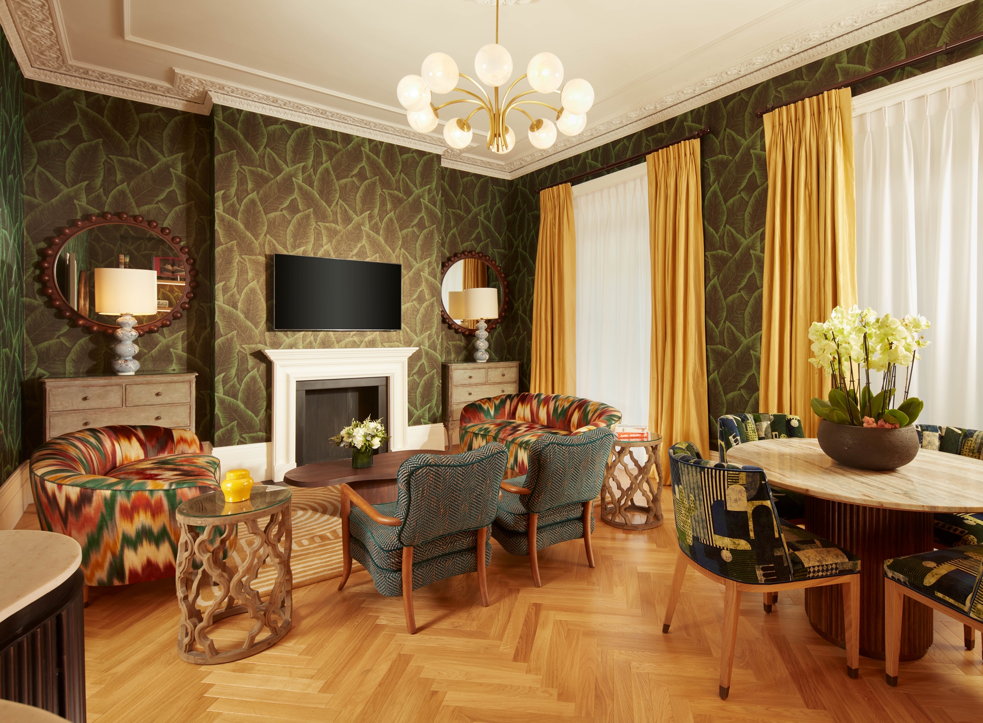 Luxurious living room in a three-bedroom suite, featuring colorful chairs, a round dining table, and elegant decor.