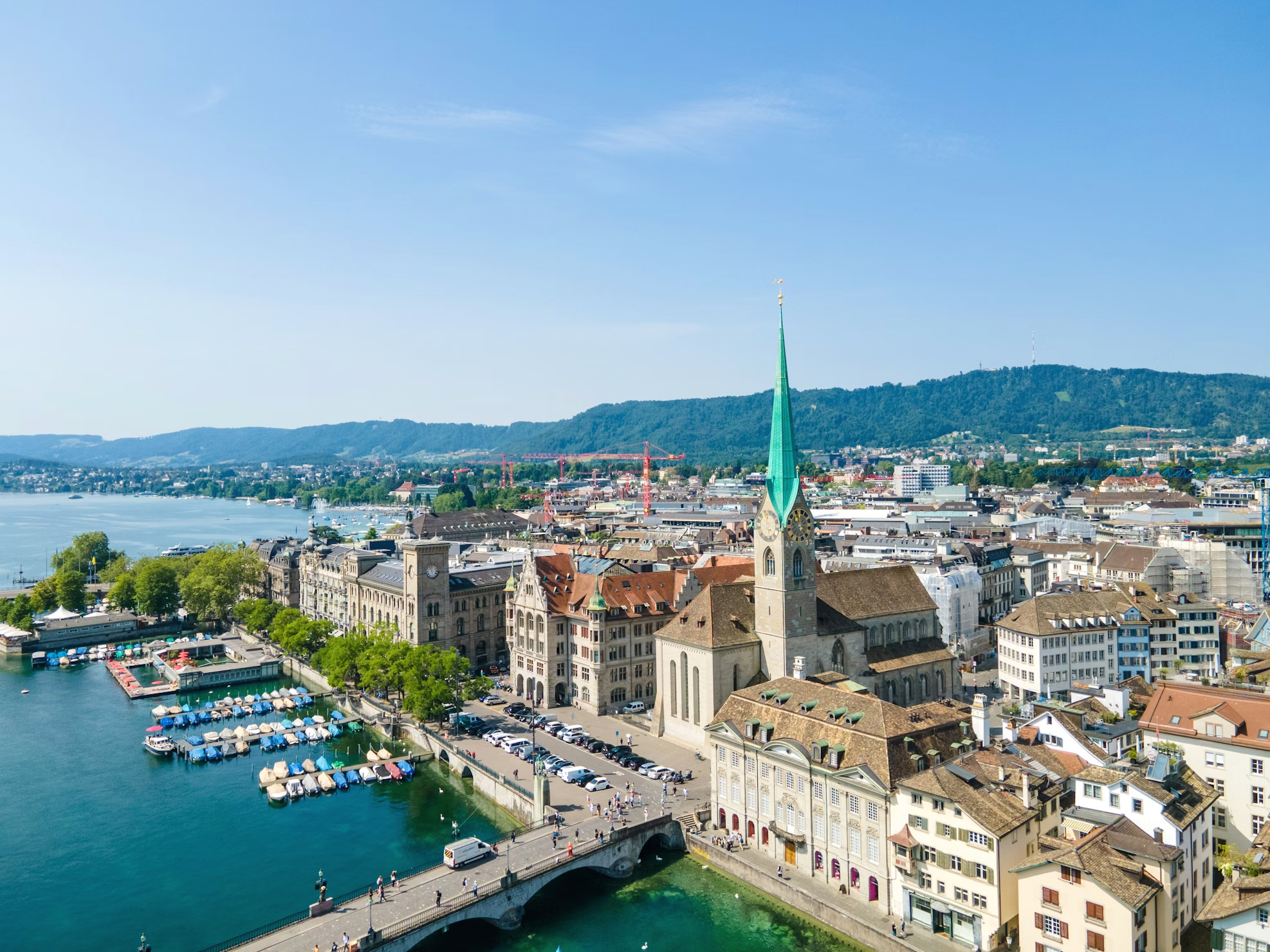 Aerial view of Zurich, featuring the green-tipped Fraumünster church and the Limmat river with boats.