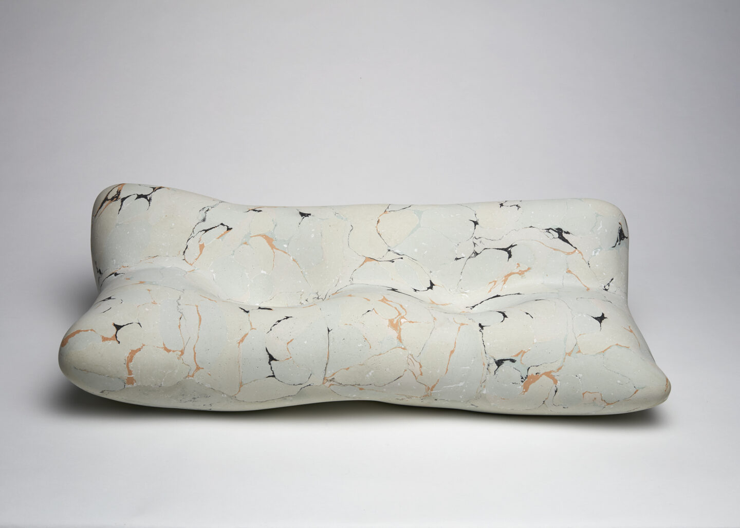 Abstract, marbled elbow pillow in soft colors of white, gray, and hints of orange, designed by Laura Dominici.