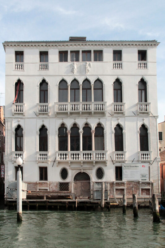 Palazzo Garzoni, a restored 15th-century Gothic palace on the Grand Canal in Venice, featuring ornate windows and a white ...