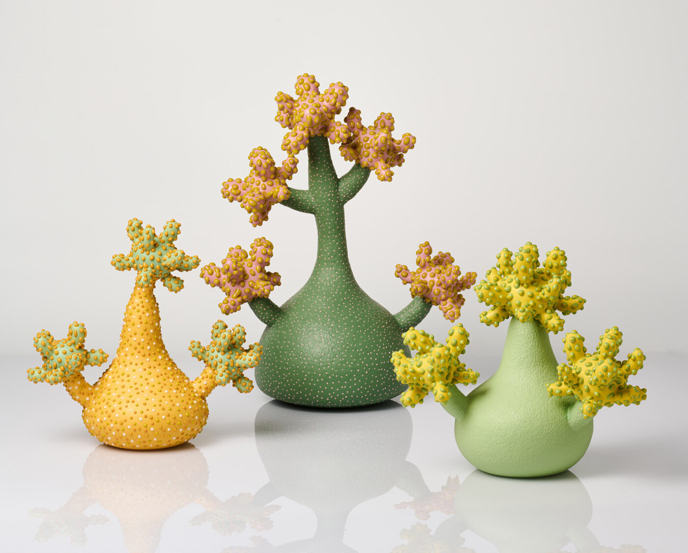 Colorful, abstract plant-like sculptures in yellow, green, and orange, featuring textured surfaces and whimsical shapes.