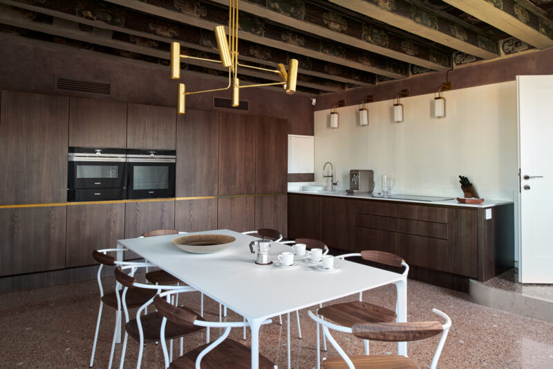 Modern kitchen in Palazzo Garzoni with wooden cabinets, white table, and stylish lighting fixtures.