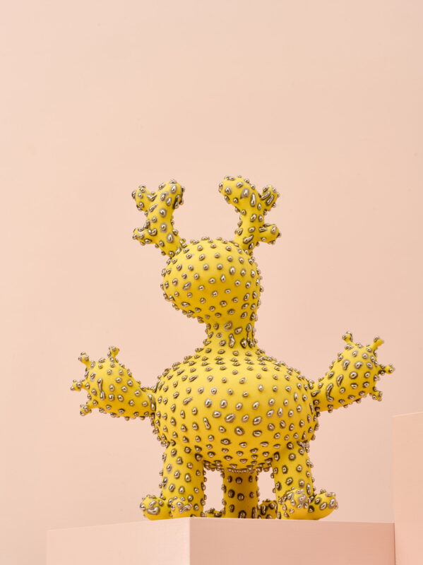 Yellow, spiky creature sculpture with silver embellishments, displayed against a soft pink background.
