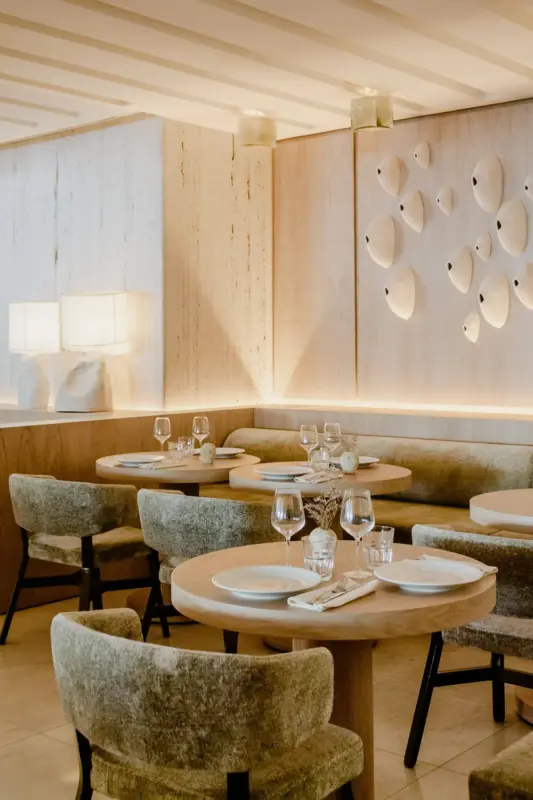 Elegant restaurant interior featuring wooden tables, plush chairs, and decorative wall art. Soft lighting enhances the amb...