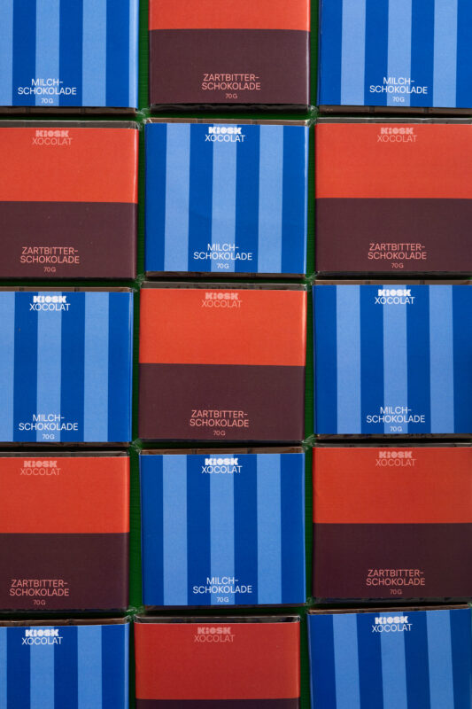 Colorful chocolate boxes arranged in a grid, featuring blue and red stripes with labels for milk and dark chocolate.