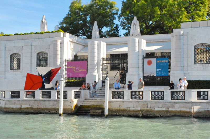 Exterior view of the Peggy Guggenheim Museum in Venice, featuring a sculpture and visitors along the canal.