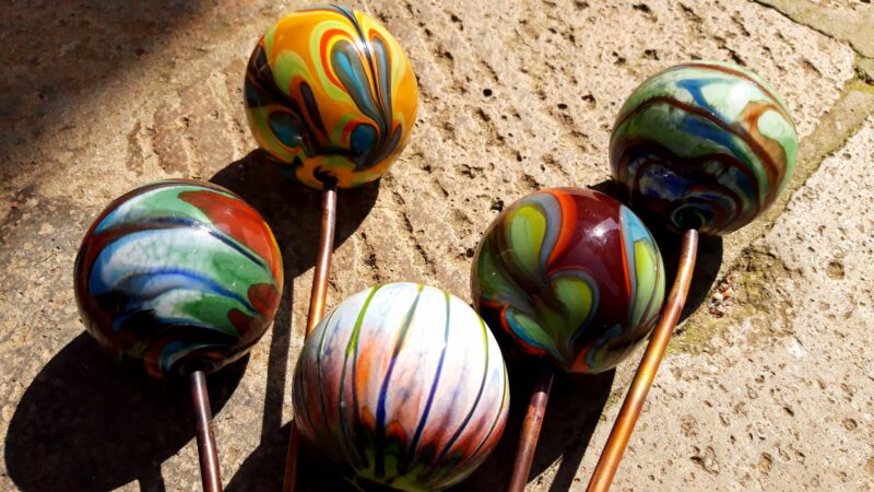 Colorful Murano glass spheres with intricate swirling patterns, arranged on a textured surface.