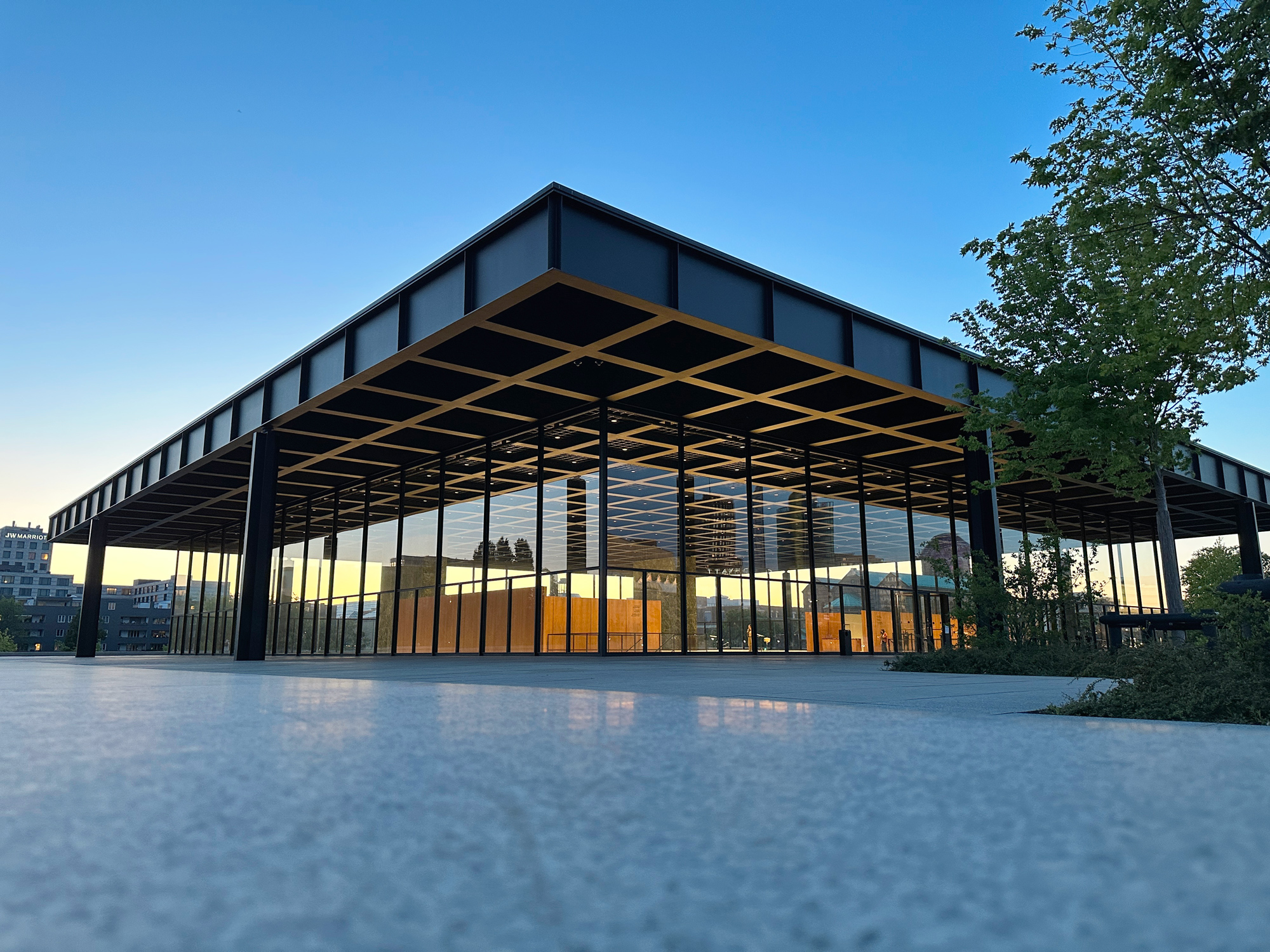 Modern architectural view of the Neue Nationalgalerie in Berlin, showcasing its glass facade and surrounding greenery.