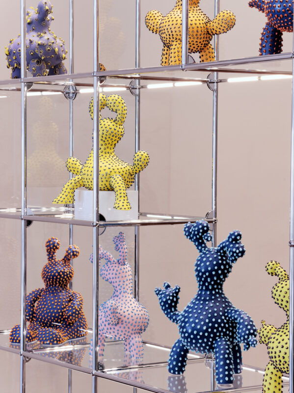 Colorful polka-dotted sculptures displayed on a modern shelving unit in the USM New York showroom.