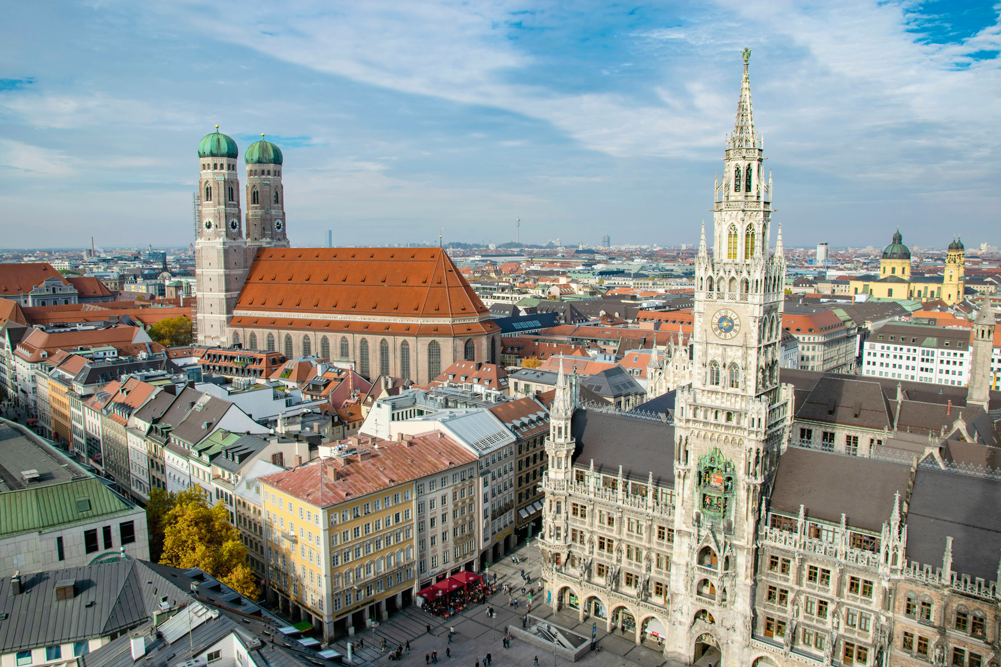 Aerial view of Munich, featuring the New Town Hall and twin towers of the Frauenkirche under a cloudy sky.
