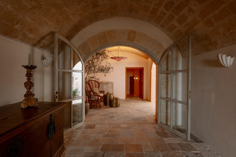 Arched entrance leading to a warm, inviting hallway with rustic decor and soft lighting.