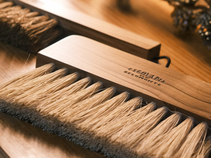 Wooden brushes with natural bristles displayed on a wooden surface, labeled "Escovaria Belomonte.