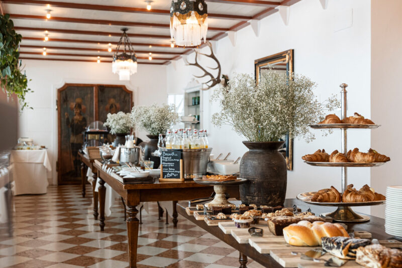 Elegant dining area at Castel Fragsburg featuring a buffet with pastries, drinks, and decorative floral arrangements.