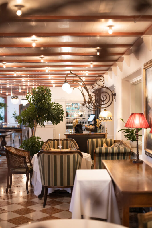Elegant restaurant interior at Castel Fragsburg, featuring striped seating, soft lighting, and decorative plants.