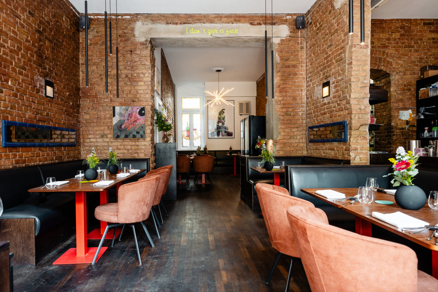 Interior of Restaurant BRIKZ featuring brick walls, wooden floors, and tables set with flowers and tableware.