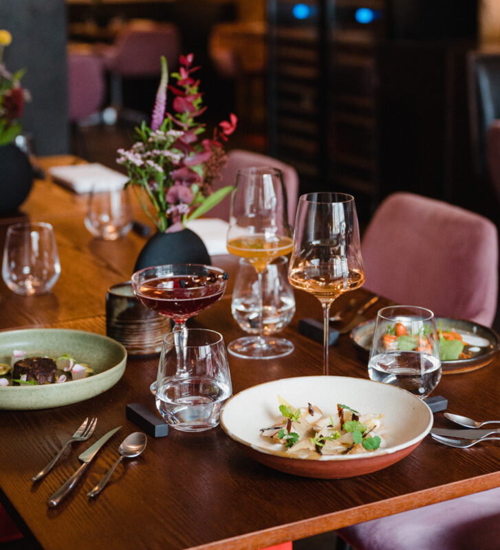 Elegant table setting at Restaurant Brikz with various dishes, glasses, and a floral centerpiece.
