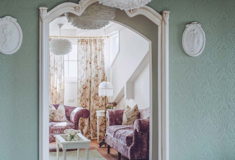 Luxurious suite at Hotel Castel Fragsburg featuring floral curtains, plush seating, and decorative wall elements.