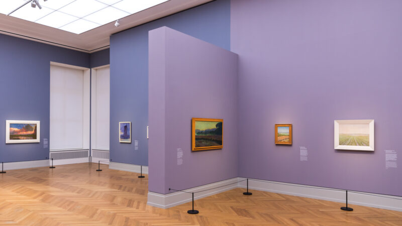 Artworks displayed on purple walls in the Museum Barberini, featuring impressionist landscapes and wooden flooring.