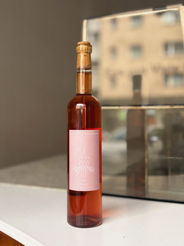 Bottle of rosé wine with a cork stopper, featuring a pink label, set against a blurred background.
