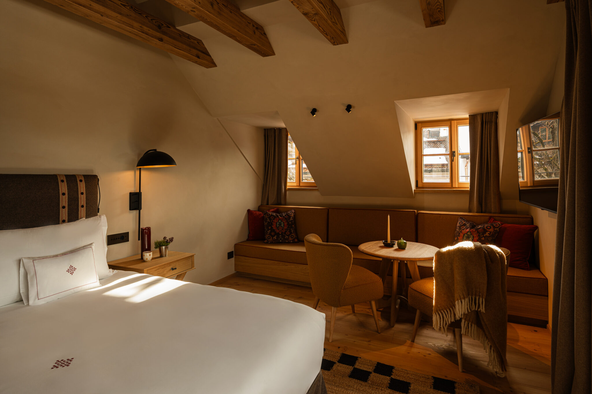 Cozy hotel room at Castel Badia featuring a bed, seating area, and warm wooden accents.