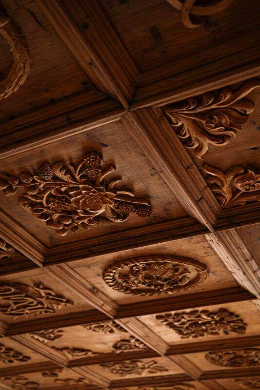 Intricately carved wooden ceiling panels featuring floral and circular designs at Castel Badia.